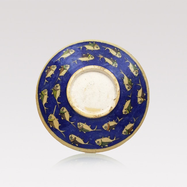 A large, round handmade Iranian serving plate with hand painted colourful fish pattern on blue.