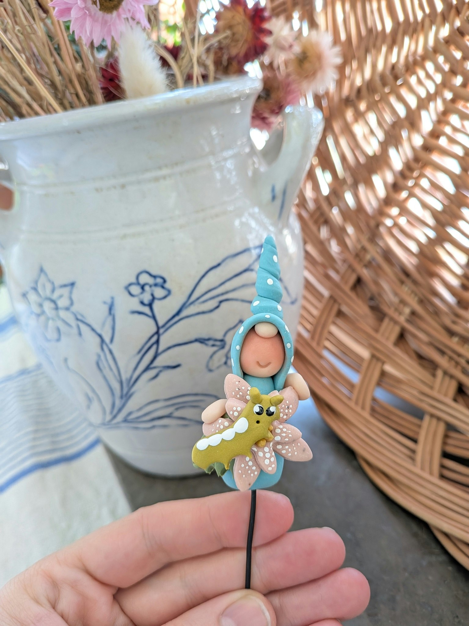 Blompinne- 'Turkos nisse med rosa blomma och grön larv'