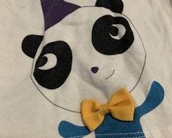Vit tröjbody med en panda framtill med en partyhatt och 3d rosett från PoP stl 68