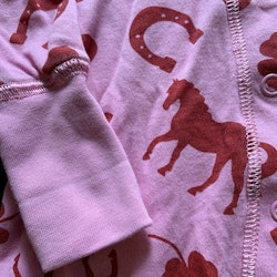 Rosa pyjamas med rött mönster av hästar, hjärtan fyrklöver och hästskor från PoP stl 56