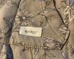 Ljusbrun jumpsuit med blommönster i mörkgrått, vitt och lila från Newbie stl 56