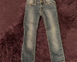 Jeans och en gråmelerad t-shirt med svart tiger- och texttryck från Mini Rodini stl 92/98