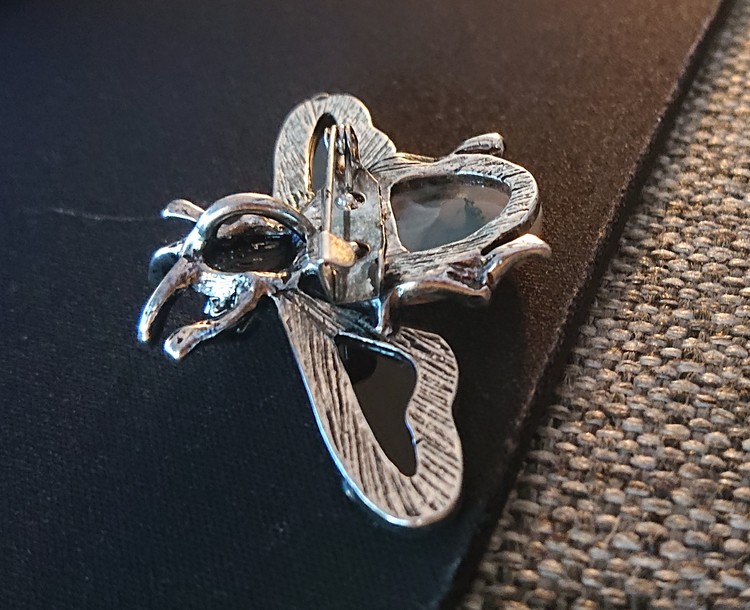 Brosch/berlock i form av en fluga med blå Guldsten och antikt silverfärgade detaljer