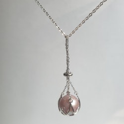 En stor rosa pärla i en silverkorg med kedja