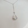 En stor vit pärla i en silverkorg med kedja