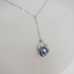 En stor blå-violett pärla i en silverkorg med kedja
