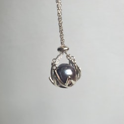 En stor blå-violett pärla i en silverkorg med kedja