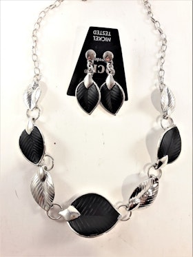 Silverfärgad halskedja med detaljer, löv i svart och silverfärg och matchande örhänge