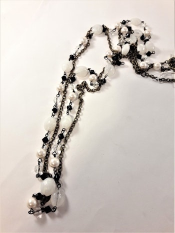 Flerradigt långt halsband med olikformade detaljer i svart och vitt