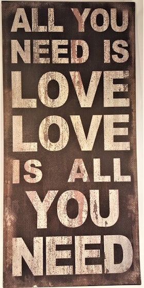 Plåttavla med texten "All you need is love...".