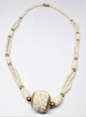 Halsband i ben med kulor i gul metall