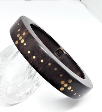 Stelt armband av trä med guldfärgat mönster