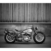 Svartvitt fotografi Harley Davidson vid brädvägg.