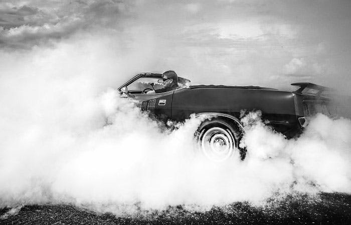 Svartvitt fotografi av en Usa bil som bränner däck. Poster.