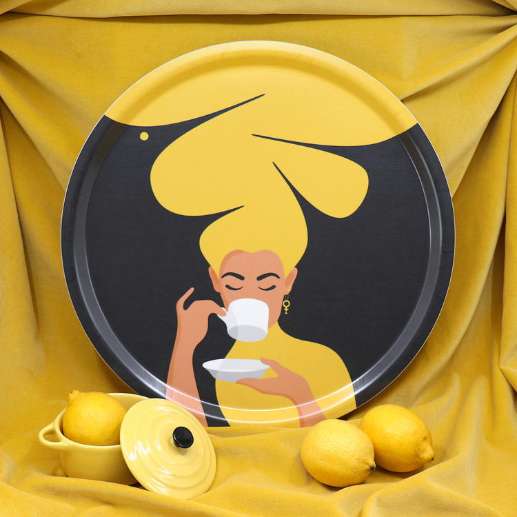 Rund bricka med motivet Kaffekvinna i gult. Kaffekvinnan har stort böljande hår, bär ett feministörhänge och njuter av en kopp kaffe.