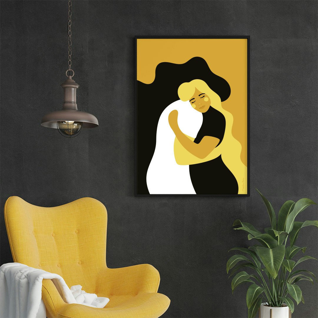 Poster med mjuka, böljande former föreställande två personer som kramas. Motivet heter Kram och går i färgerna svart, vitt, gult och senapsgult. Här inramat på en vägg bredvid en gul fåtölj.