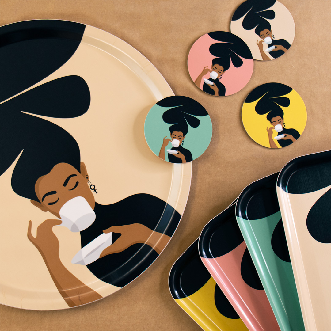 Rund bricka, coasters /glasunderlägg och mindre rektangulära brickor med motivet Kaffekvinnan – en kvinna med stort bubbligt hår som dricker kaffe ur en kaffekopp. Färger: sand, mint, rosa och gul.
