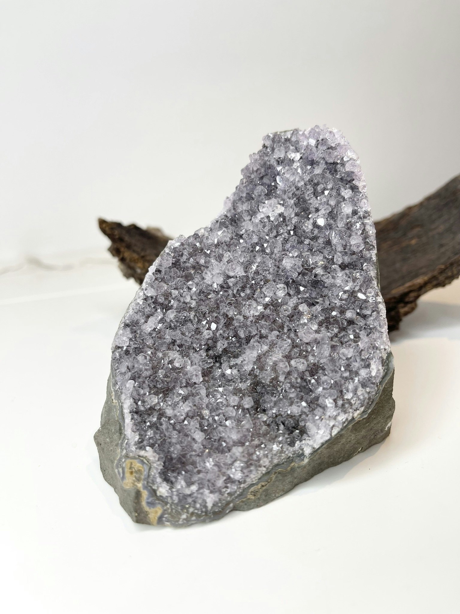 Ametist-sten med djup textur och fasetterad yta, placerad på en vit yta