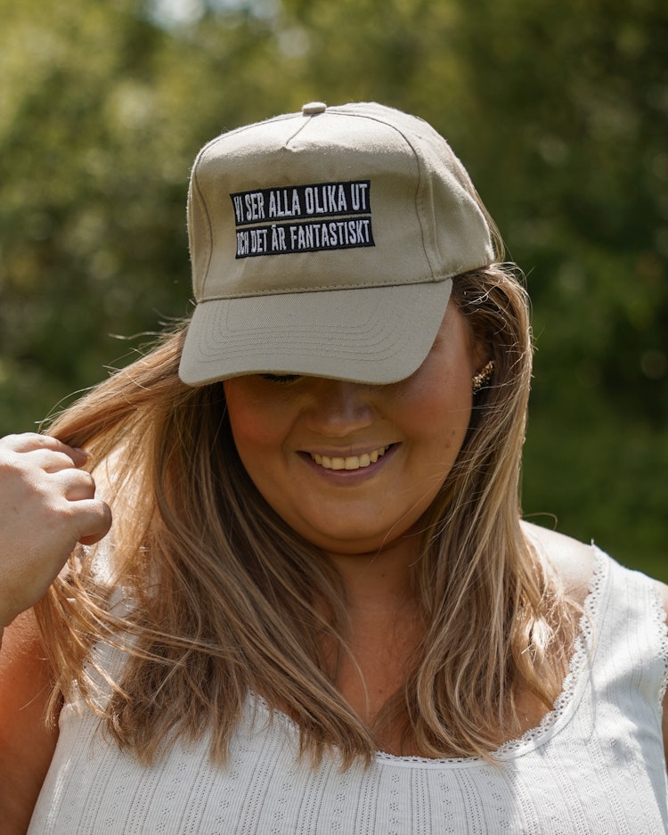 Beige keps "Vi ser alla olika ut och det är fantastiskt"