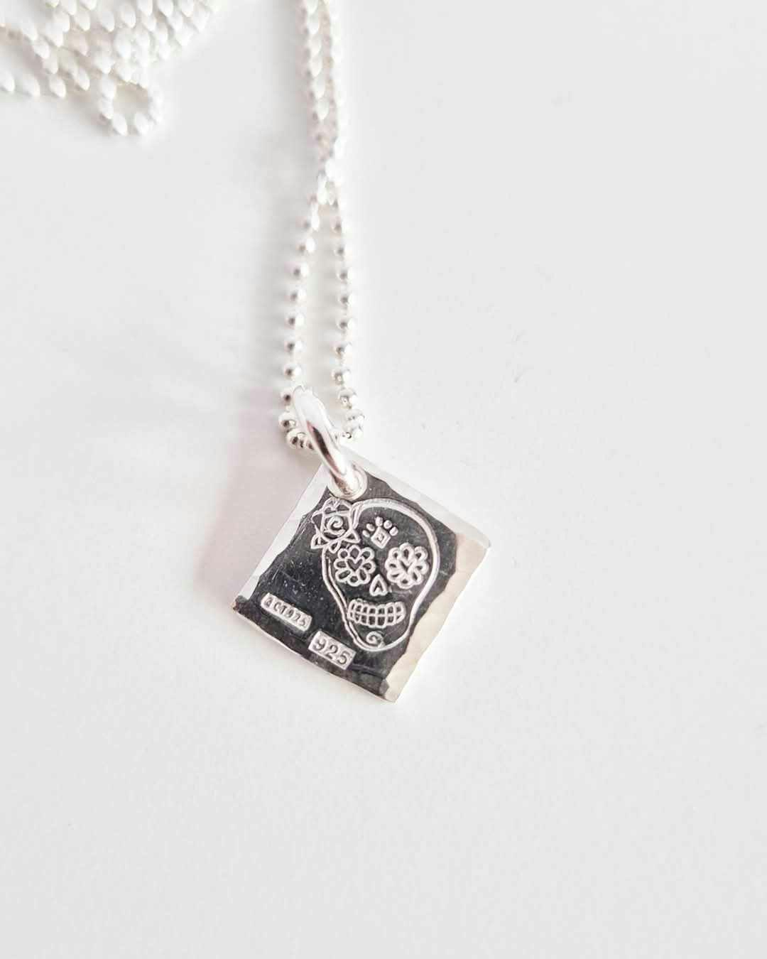 Ett fint silverhalsband med en döskalle i äkta silver HER på en silverbricka