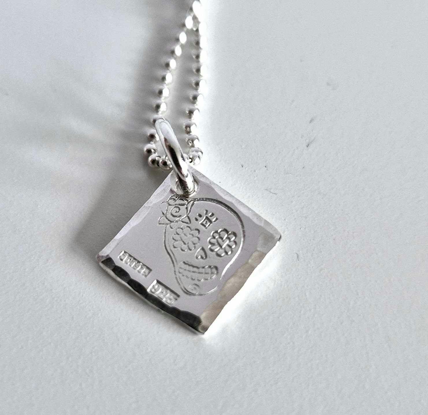 Ett fint silverhalsband med en döskalle i äkta silver HER på en silverbricka