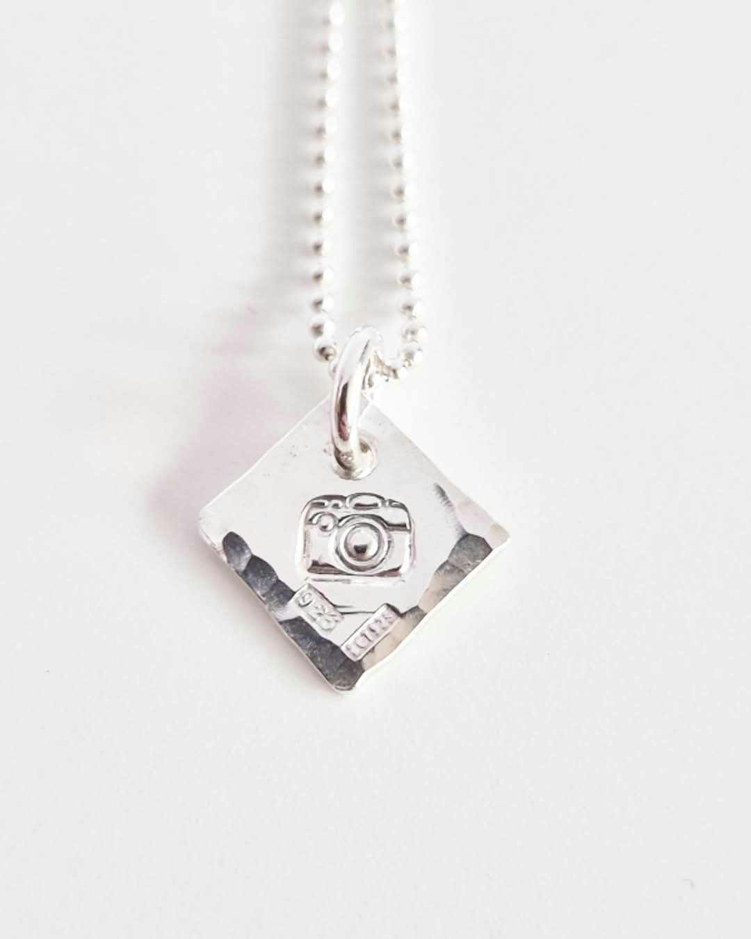 Ett fint silverhalsband med en kamera Fokus