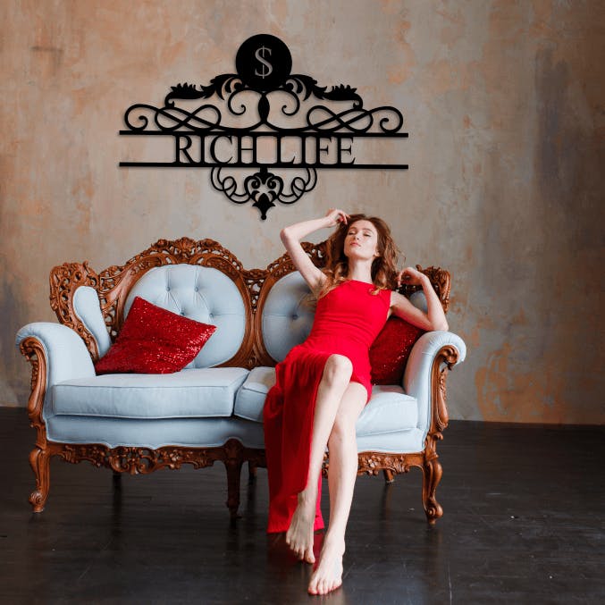 Rik kvinna sittandes i soffa, med en personlig skylt på väggen bakom med texten Rich Life.