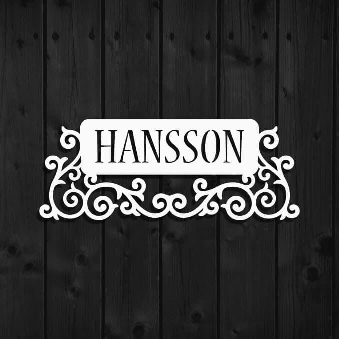 Snygg dekor i plåt med krusiduller och namnet Hansson utskuret.
