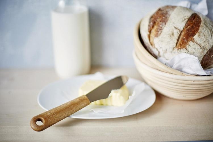 Naturfärgad smörkniv i rostfritt stål med skaft av bioplast och träfiber i köksmiljö.