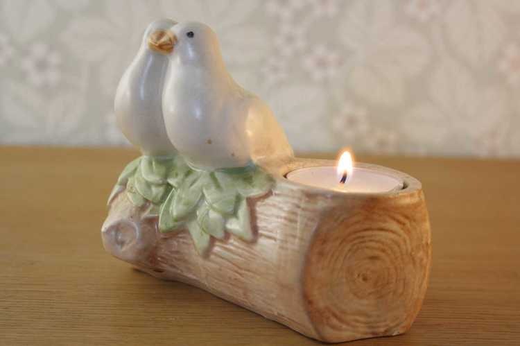 Ljusstake för värmeljus i keramik med två duvor som sitter på en pinne fotad från sidan