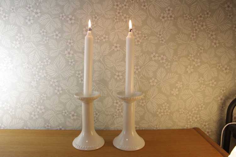 Två stycken vita ljusstakar med brinnande kronljus av modell Tiara från Rörstrand