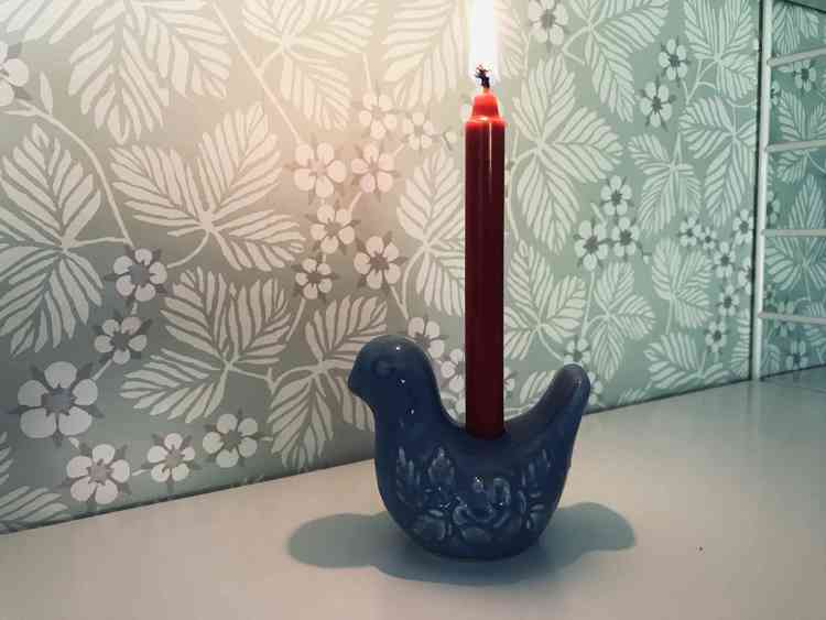 Ljusstake i keramik av blå fågel med ett rött julgransljus