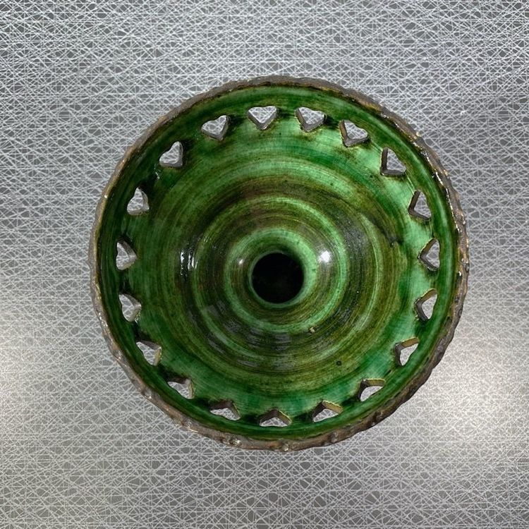 Ljusstake på fot i keramik med grön glasering och perforerad kant tagen ovanifrån