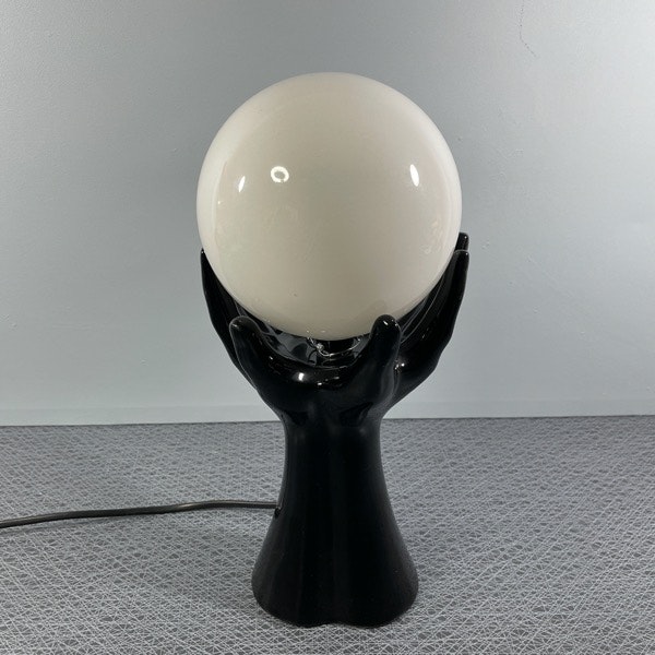 handlampa svart porslin händer som håller en en glaskula perspektiv