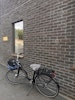Cykelsadelskydd Grå tagen på en cykel lutad mot en tegelvägg