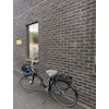 Cykelsadelskydd Grå tagen på en cykel lutad mot en tegelvägg