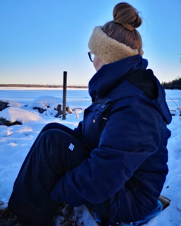 Kvinna tittar ut mot en frysen sjö i snö