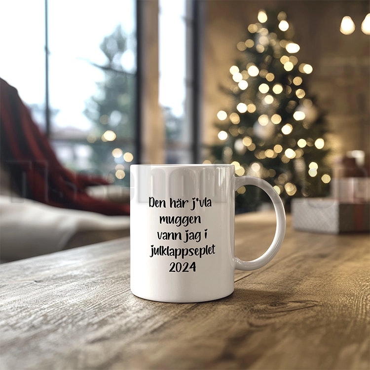 Vit keramisk mugg med texten "Den här j*vla muggen vann jag i julklappspelet 2024", 330 ml, med tryck på båda sidor.  Nr 1