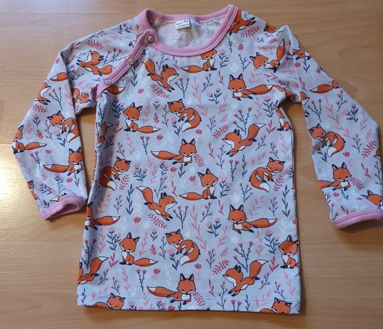 Bilden föreställer en långärmad tröja med rävar i ekologisk jersey/trikå.