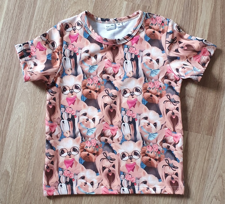 Bilden föreställer en T-shirt med gulliga hundar i ekologisk jersey/trikå.
