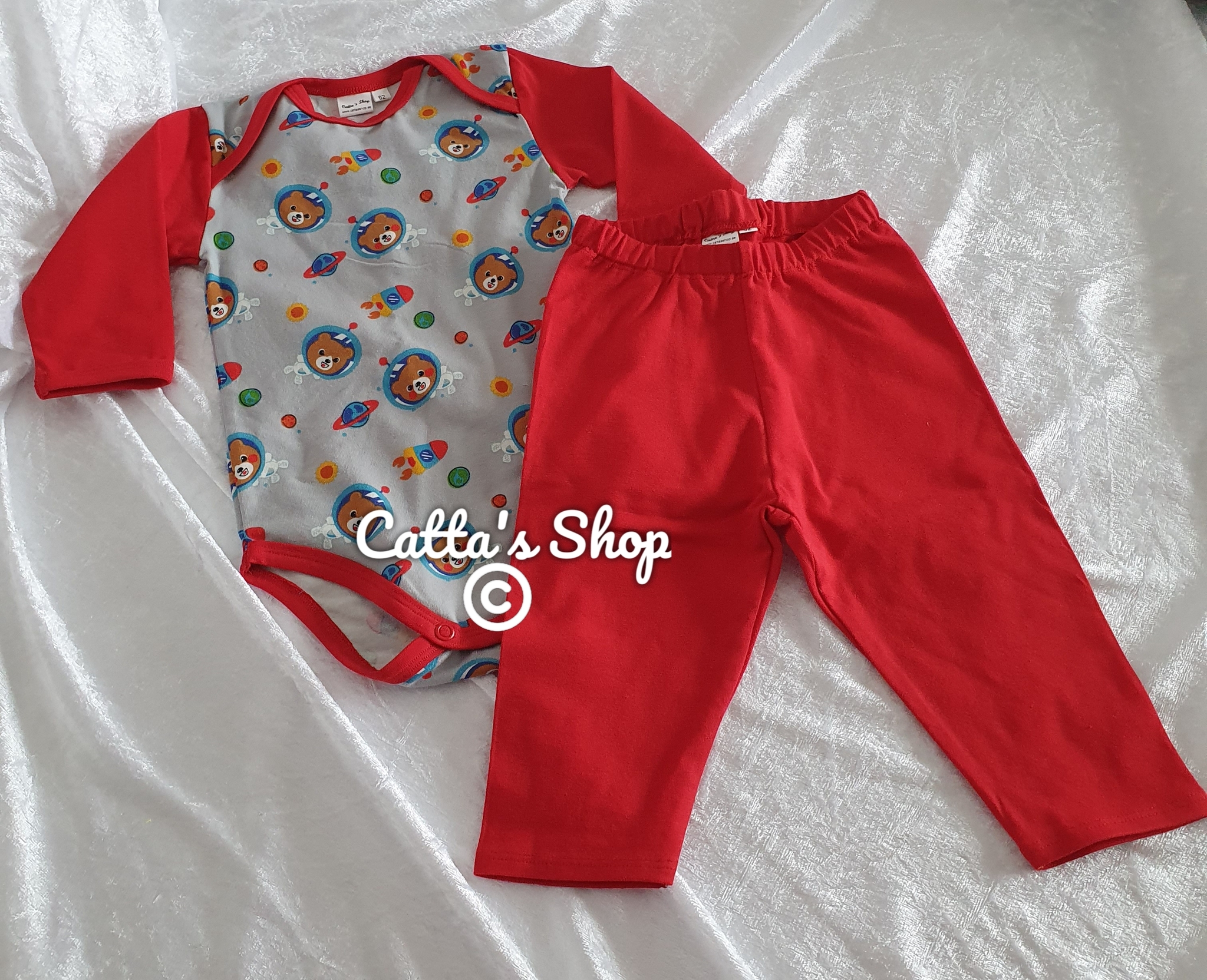 Bilden föreställer babybody med motiv rymdnallar och enfärgade byxor röd sydd i ekologisk jersey.