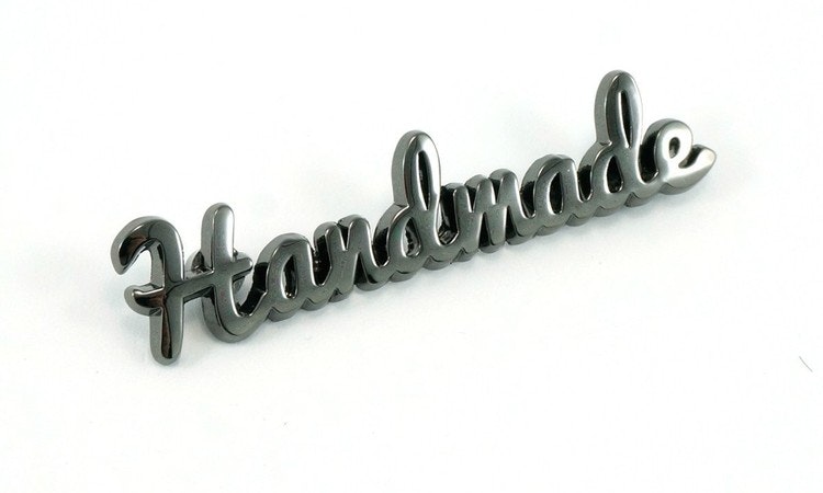 Metal bag label: "handmade", script style