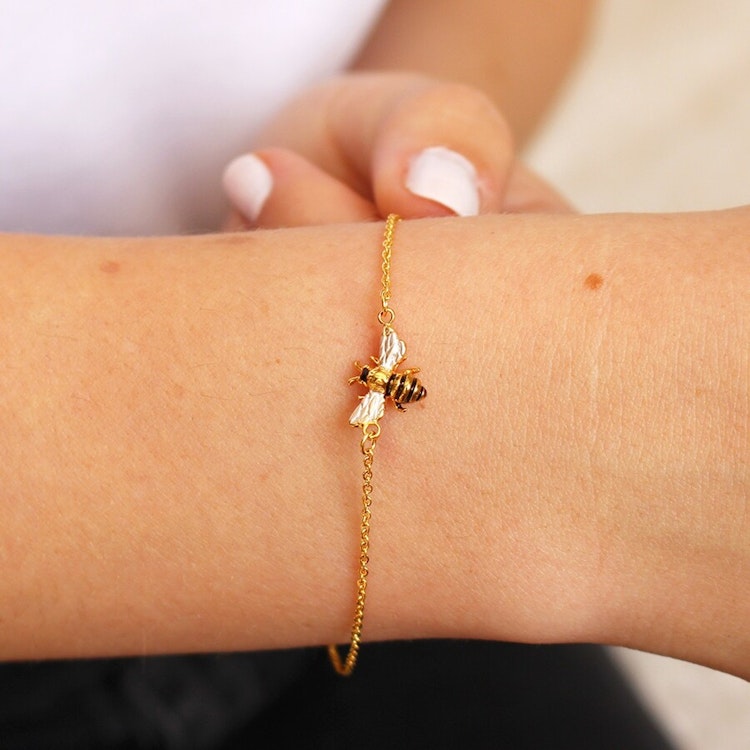 Bild på ett guldpläterat armband med ett litet bi.
