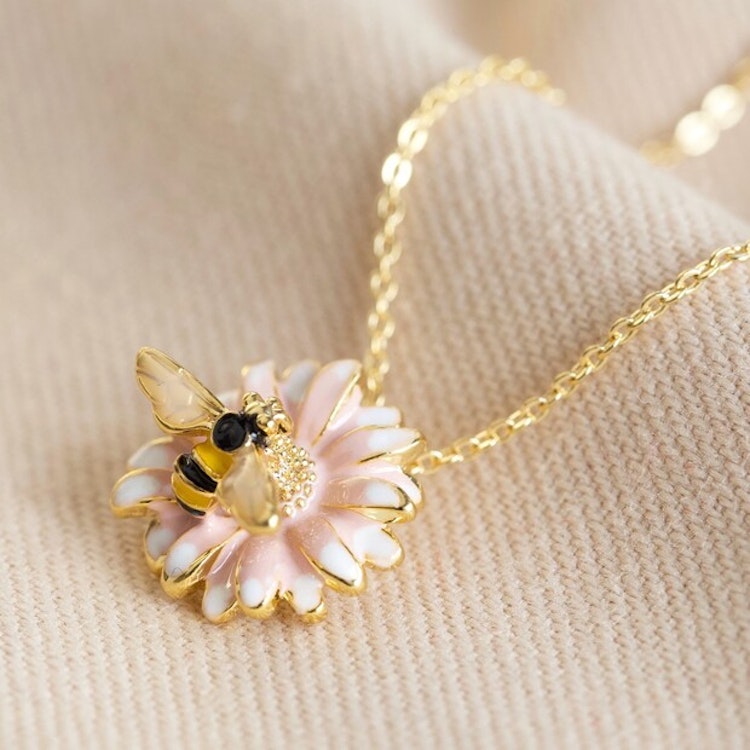 Bild på ett halsband med en tusensköna med ett bi på.