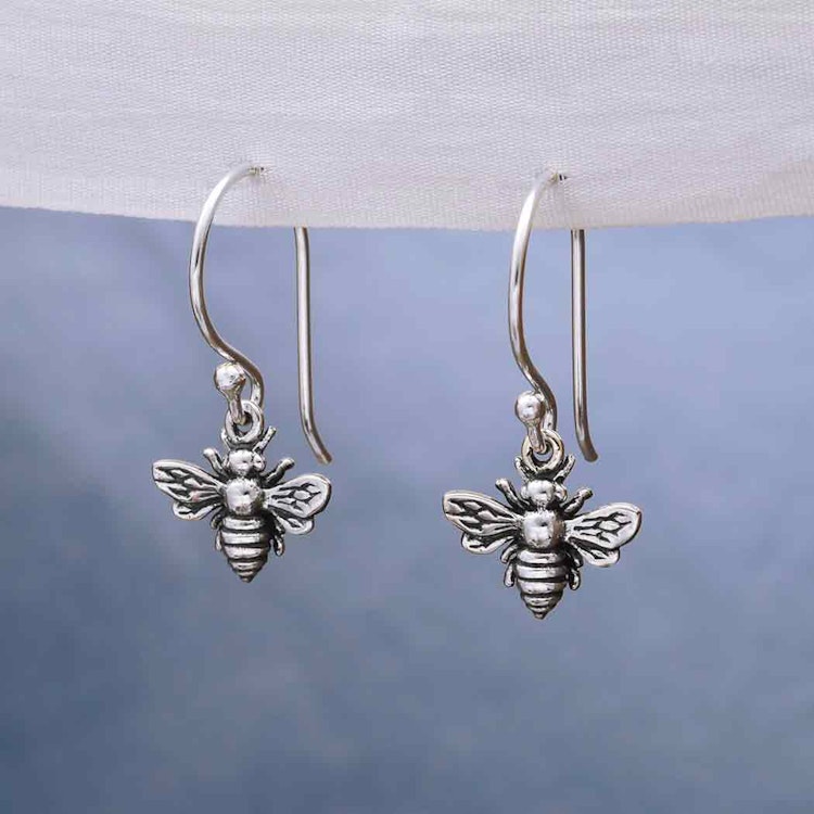 Bild som visar ett par silverörhängen i form av bin som dinglar på krokar