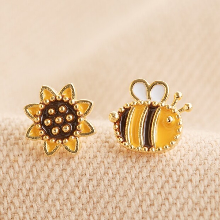Bild på örhängen där det ena är en solros och det andra ett bi
