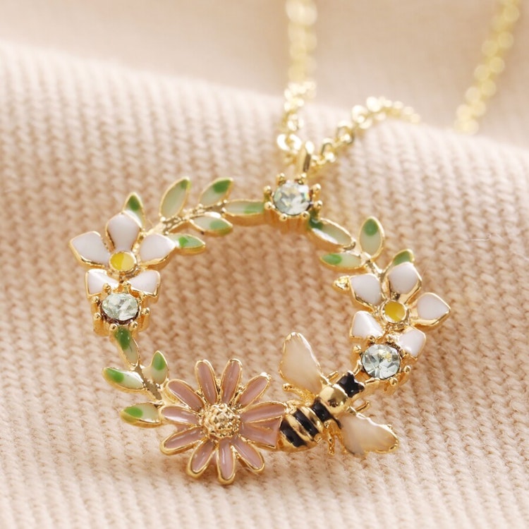 Bild på ett halsband med en blomsterkrans med ett litet bi – guld