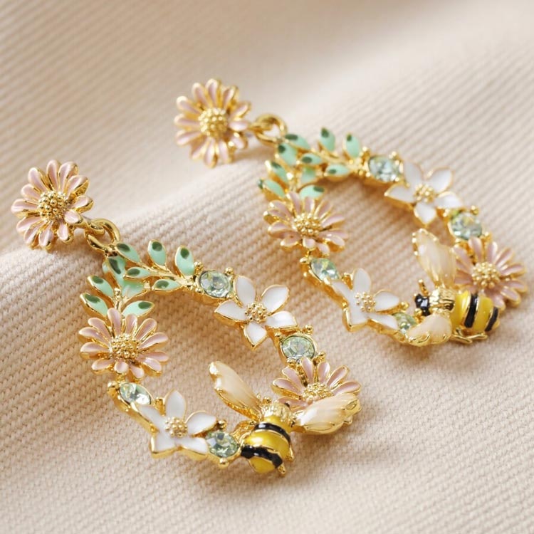 Bild på ett par droppformade örhängen fyllda med blommor och ett litet bi