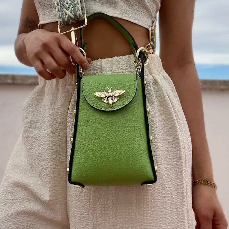 Bild som visar en grön handväska med ett guldfärgat bispänne