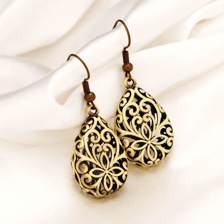 Bilden visar två droppformade örhängen med orientaliskt inspirerat mönster.